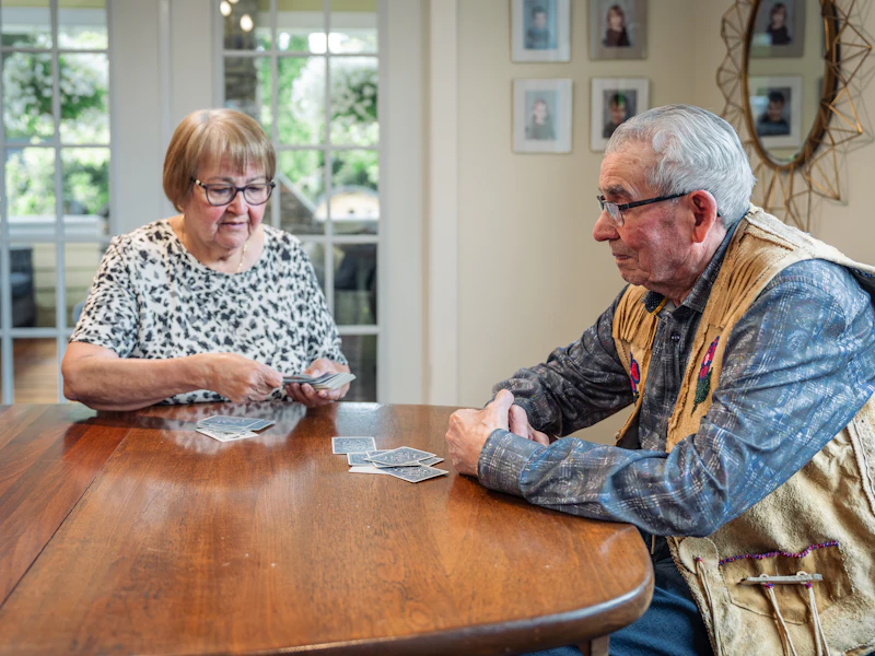 An older couple playing cards together at their dining table at home