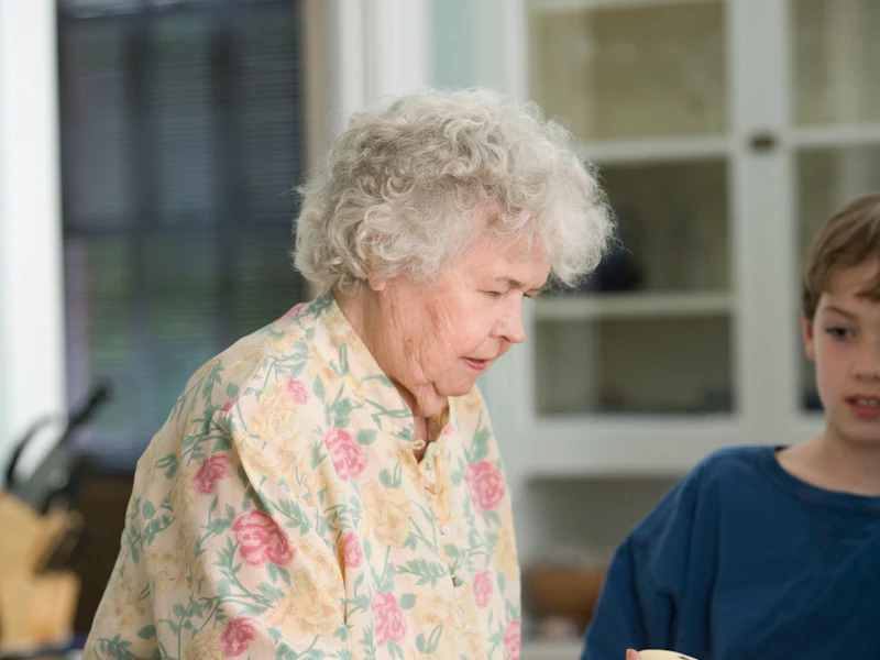 An older woman and a young relative talking together in a home kitchen